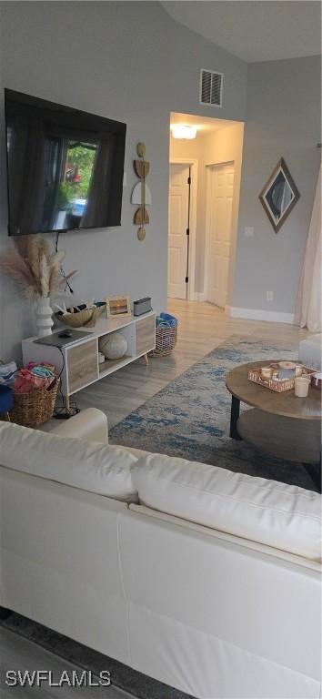 living area featuring visible vents and vaulted ceiling