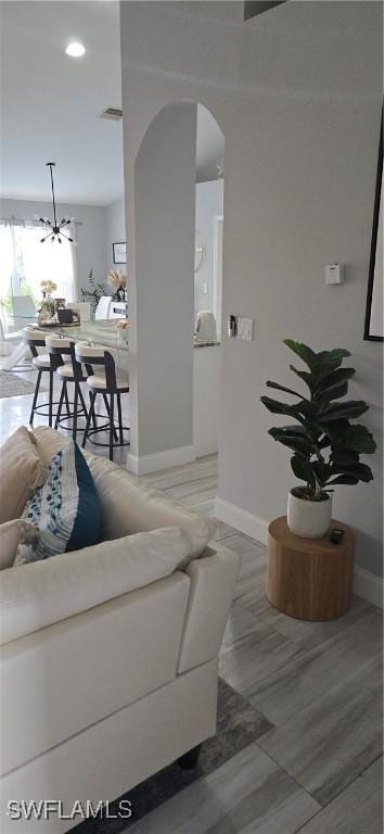 living area with arched walkways, visible vents, and baseboards