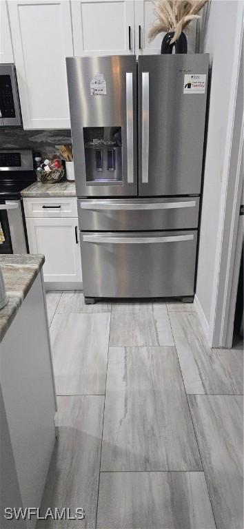 kitchen featuring tasteful backsplash, appliances with stainless steel finishes, light stone countertops, and white cabinets