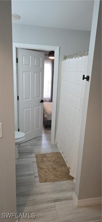 bathroom with curtained shower, toilet, and baseboards