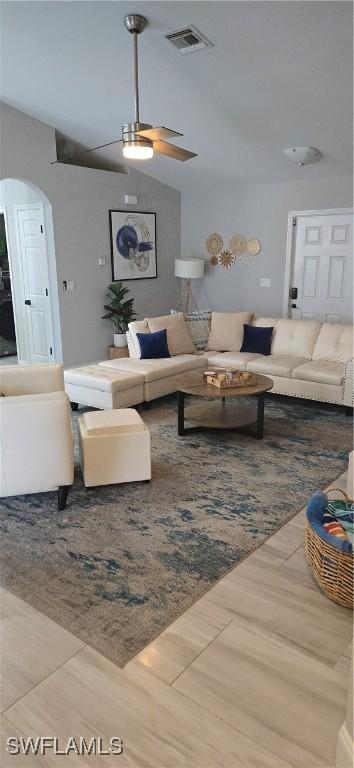 living room with arched walkways, wood finished floors, and visible vents