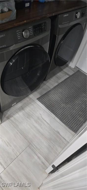 clothes washing area with laundry area, washer and dryer, and tile patterned floors