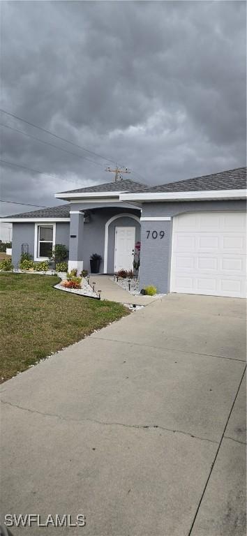 ranch-style home featuring a garage, a front yard, driveway, and stucco siding