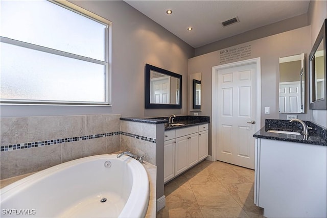 bathroom with recessed lighting, two vanities, a sink, visible vents, and a bath