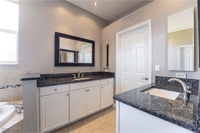 bathroom with tile patterned floors, two vanities, a sink, and a bath