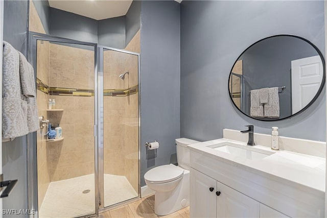 bathroom with toilet, a stall shower, and vanity