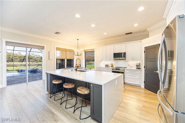 kitchen featuring light wood finished floors, visible vents, a spacious island, stainless steel appliances, and a sink