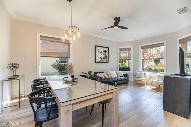 dining space with crown molding, visible vents, and light wood-style floors