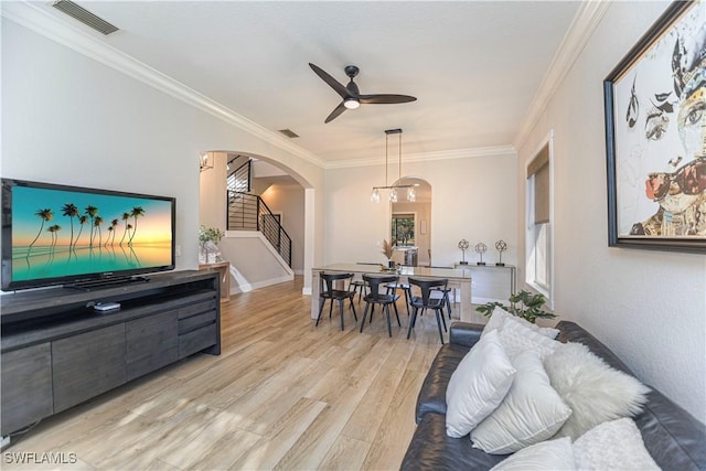 living room with light wood-style floors, stairway, visible vents, and arched walkways