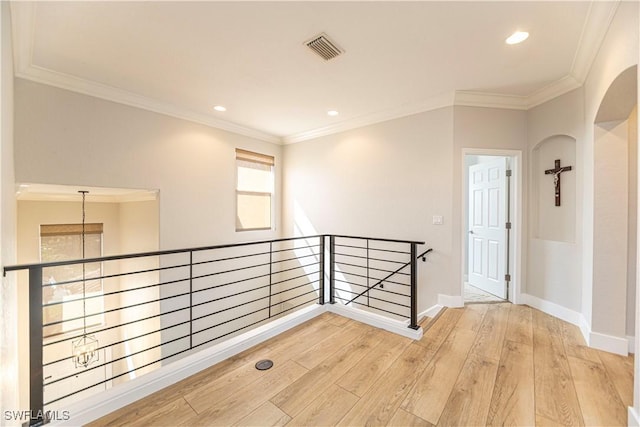 hallway featuring crown molding, visible vents, light wood-style flooring, an upstairs landing, and baseboards