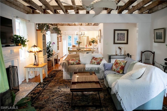 living room with a chandelier, a fireplace with raised hearth, and wood finished floors