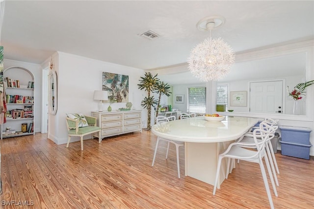 dining space featuring light wood-type flooring, visible vents, and an inviting chandelier