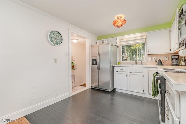 kitchen with dark wood-style flooring, light countertops, appliances with stainless steel finishes, white cabinetry, and baseboards