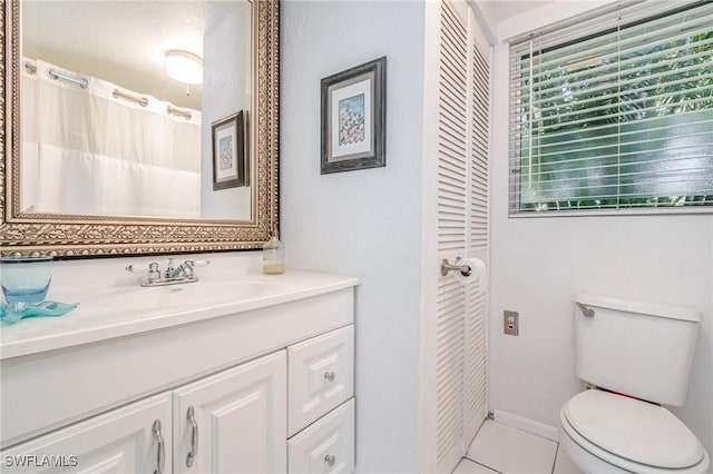 full bathroom with baseboards, toilet, tile patterned flooring, vanity, and a closet