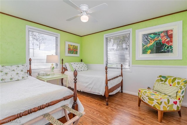 bedroom featuring light wood-style floors, ornamental molding, and a ceiling fan