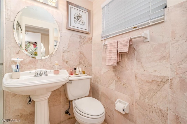 bathroom featuring toilet and tile walls