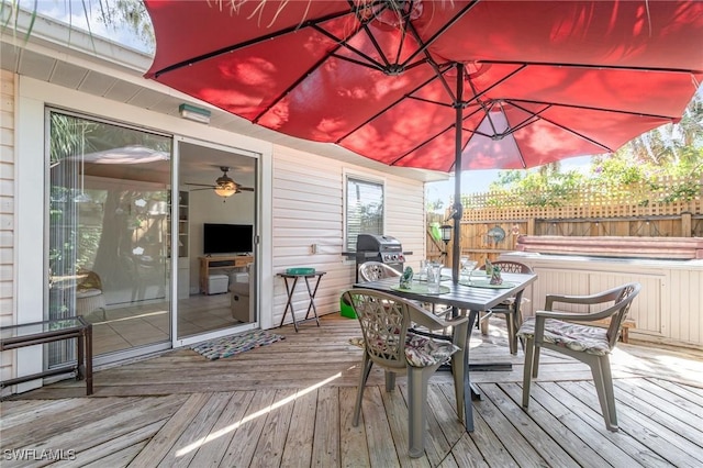 deck featuring outdoor dining area, a hot tub, fence, and grilling area