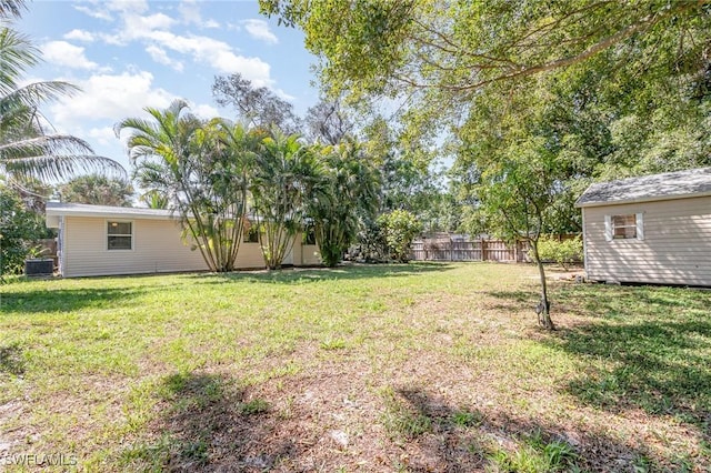 view of yard with an outbuilding, fence, and central AC unit