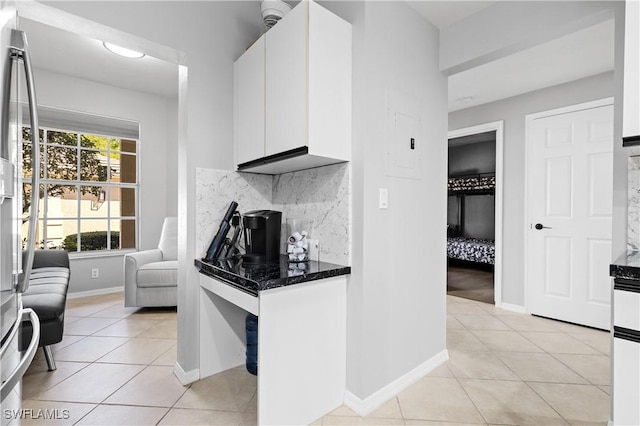 kitchen with dark countertops, white cabinets, backsplash, and light tile patterned flooring