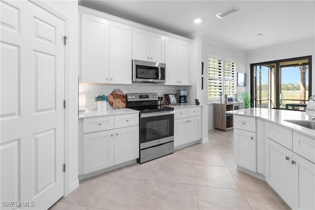 kitchen featuring light tile patterned floors, stainless steel appliances, white cabinetry, light countertops, and backsplash