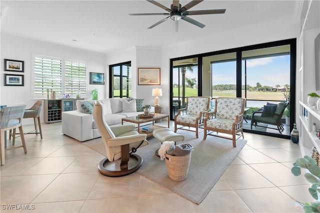 living room with a ceiling fan, crown molding, and light tile patterned floors