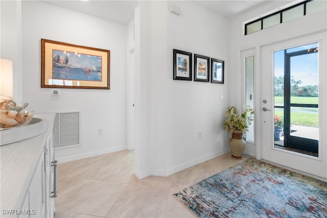 foyer entrance featuring light tile patterned floors, visible vents, and baseboards