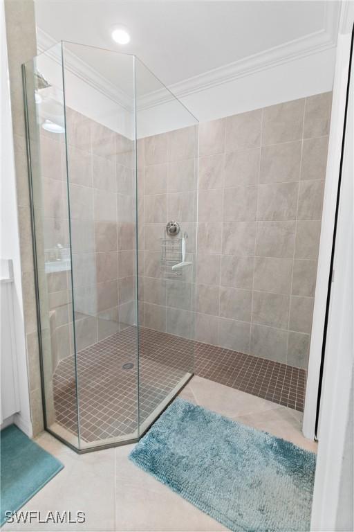 full bath with tile patterned flooring, crown molding, and a walk in shower