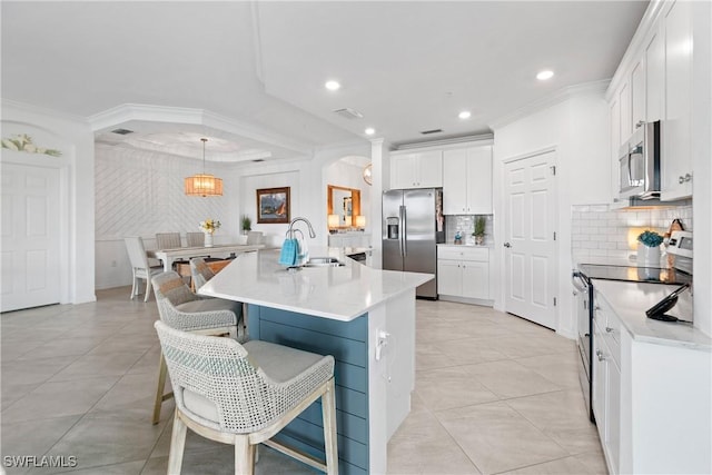 kitchen featuring white cabinets, appliances with stainless steel finishes, a kitchen breakfast bar, crown molding, and a sink