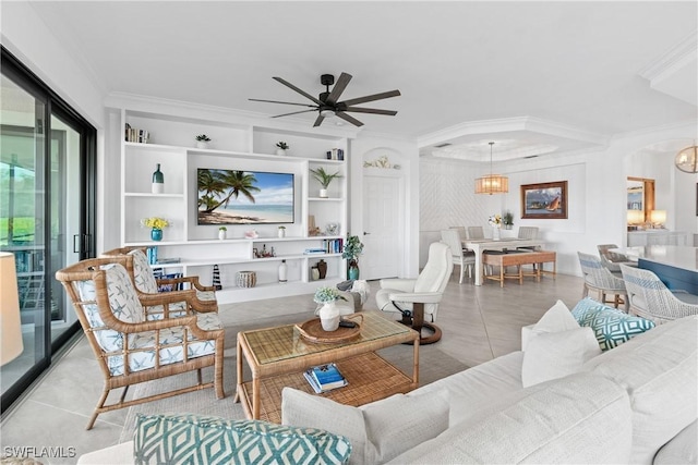 tiled living room featuring arched walkways, built in shelves, ceiling fan with notable chandelier, and crown molding