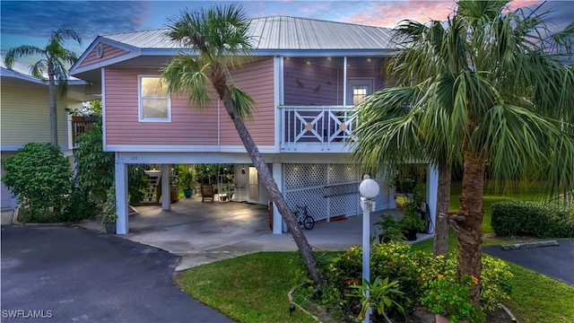 view of front of property with a carport, driveway, metal roof, and stairs