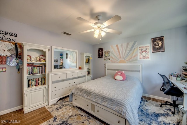 bedroom featuring a ceiling fan, visible vents, baseboards, and wood finished floors