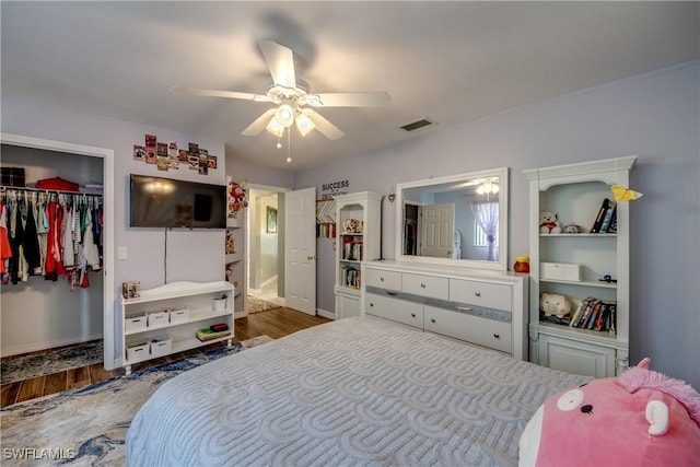 bedroom with a closet, wood finished floors, visible vents, and a ceiling fan