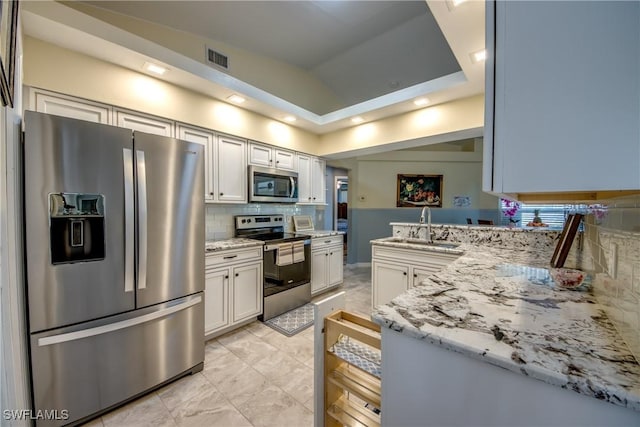 kitchen with light stone counters, stainless steel appliances, tasteful backsplash, visible vents, and a sink