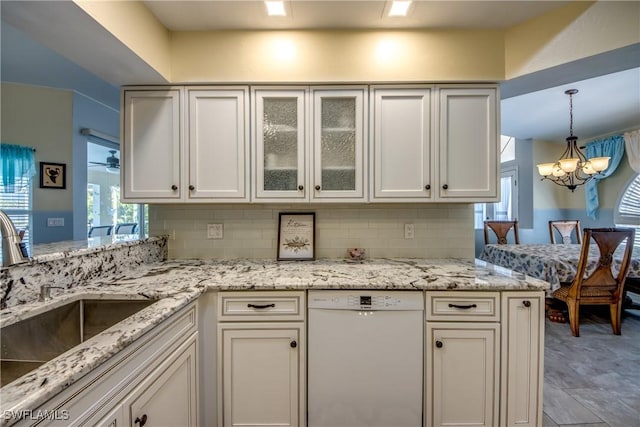 kitchen featuring dishwasher, tasteful backsplash, a sink, and light stone countertops