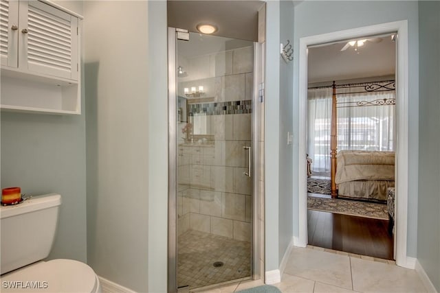 ensuite bathroom featuring toilet, ensuite bathroom, a stall shower, baseboards, and tile patterned floors