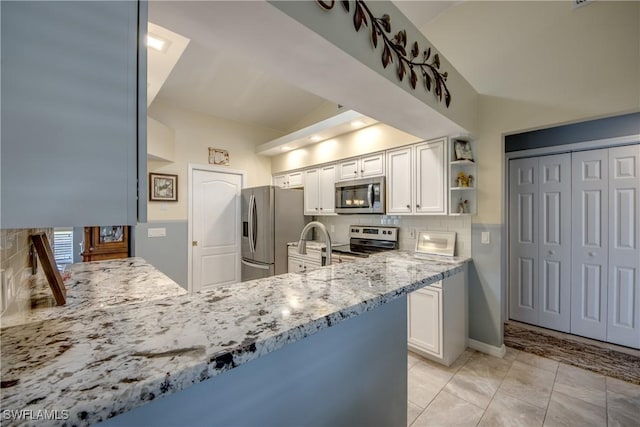 kitchen featuring stainless steel appliances, white cabinets, vaulted ceiling, light stone countertops, and tasteful backsplash