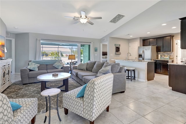 living area featuring light tile patterned floors, a ceiling fan, visible vents, recessed lighting, and vaulted ceiling