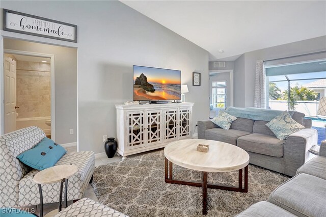 tiled living area featuring vaulted ceiling, baseboards, and visible vents