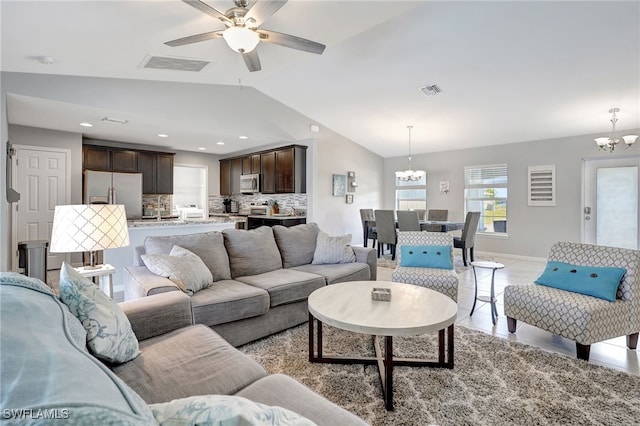 living room featuring lofted ceiling, light tile patterned floors, ceiling fan with notable chandelier, and visible vents