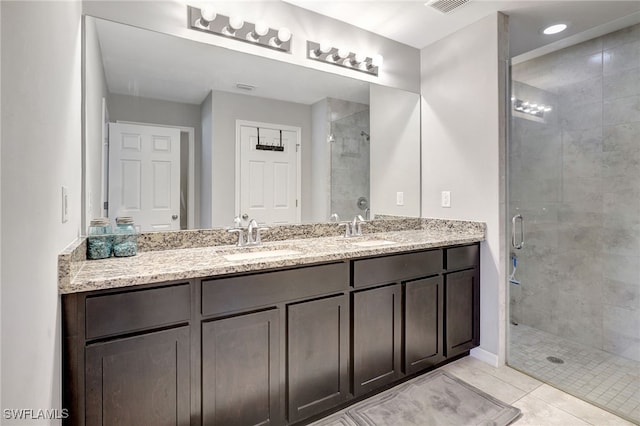 full bath with a shower stall, double vanity, and a sink