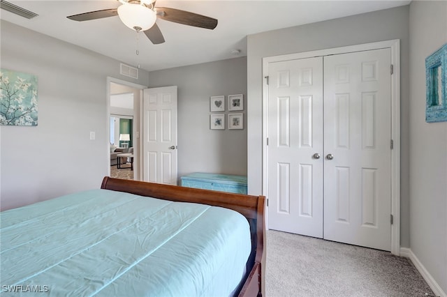 carpeted bedroom featuring a closet, visible vents, baseboards, and ceiling fan