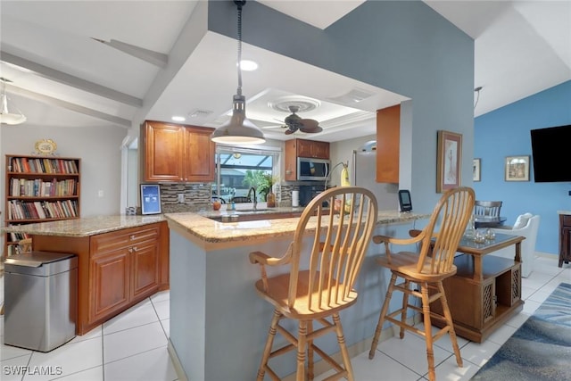 1442 SE 15th Ter, Cape Coral, FL 33990 - kitchen with stainless steel microwave, a peninsula, ceiling fan, vaulted ceiling, and decorative backsplash