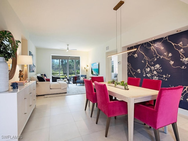 dining space featuring light tile patterned floors, ceiling fan, an accent wall, and visible vents