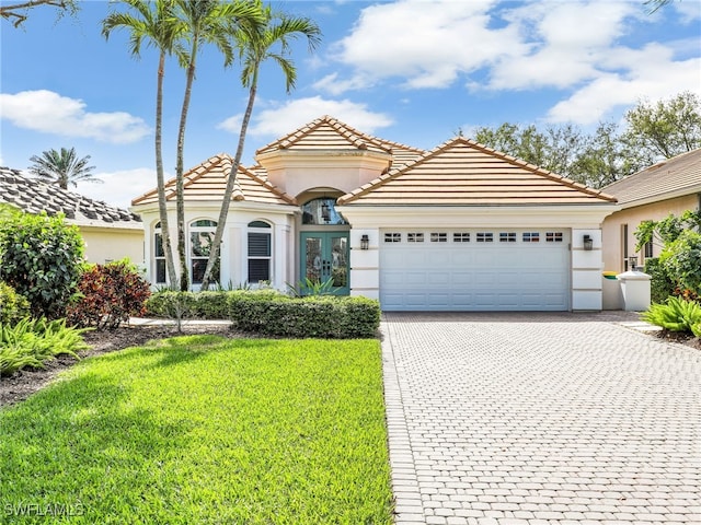 mediterranean / spanish house with a garage, french doors, decorative driveway, and stucco siding