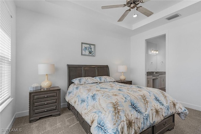 bedroom with visible vents, a raised ceiling, ensuite bathroom, carpet, and baseboards