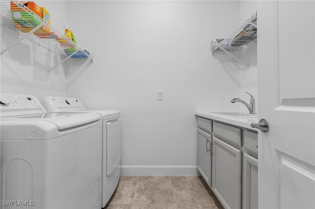 washroom with cabinet space, independent washer and dryer, baseboards, and a sink