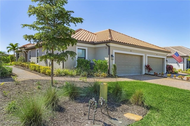 mediterranean / spanish home featuring stucco siding, a garage, driveway, and a tile roof