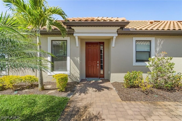 property entrance with stucco siding and a tiled roof