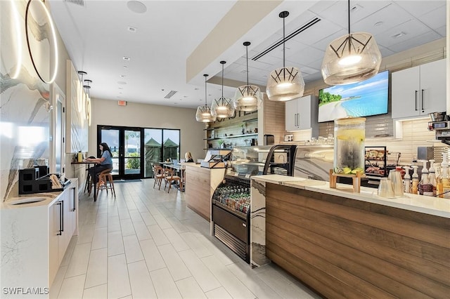 kitchen featuring hanging light fixtures, decorative backsplash, white cabinets, and modern cabinets