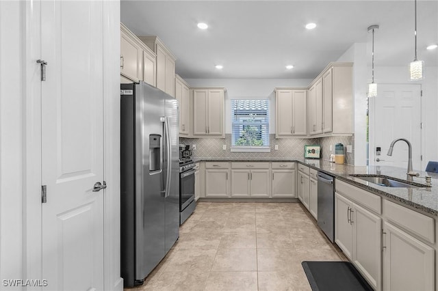 kitchen featuring dark stone countertops, a sink, stainless steel appliances, decorative light fixtures, and tasteful backsplash